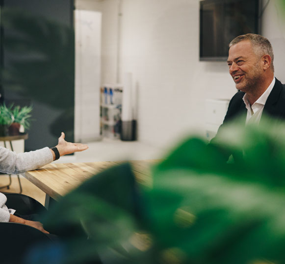 Twee mannen bespreken diensten aan een tafel in een kantoor.