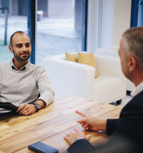 Twee experts praten aan een tafel in een kantoor.